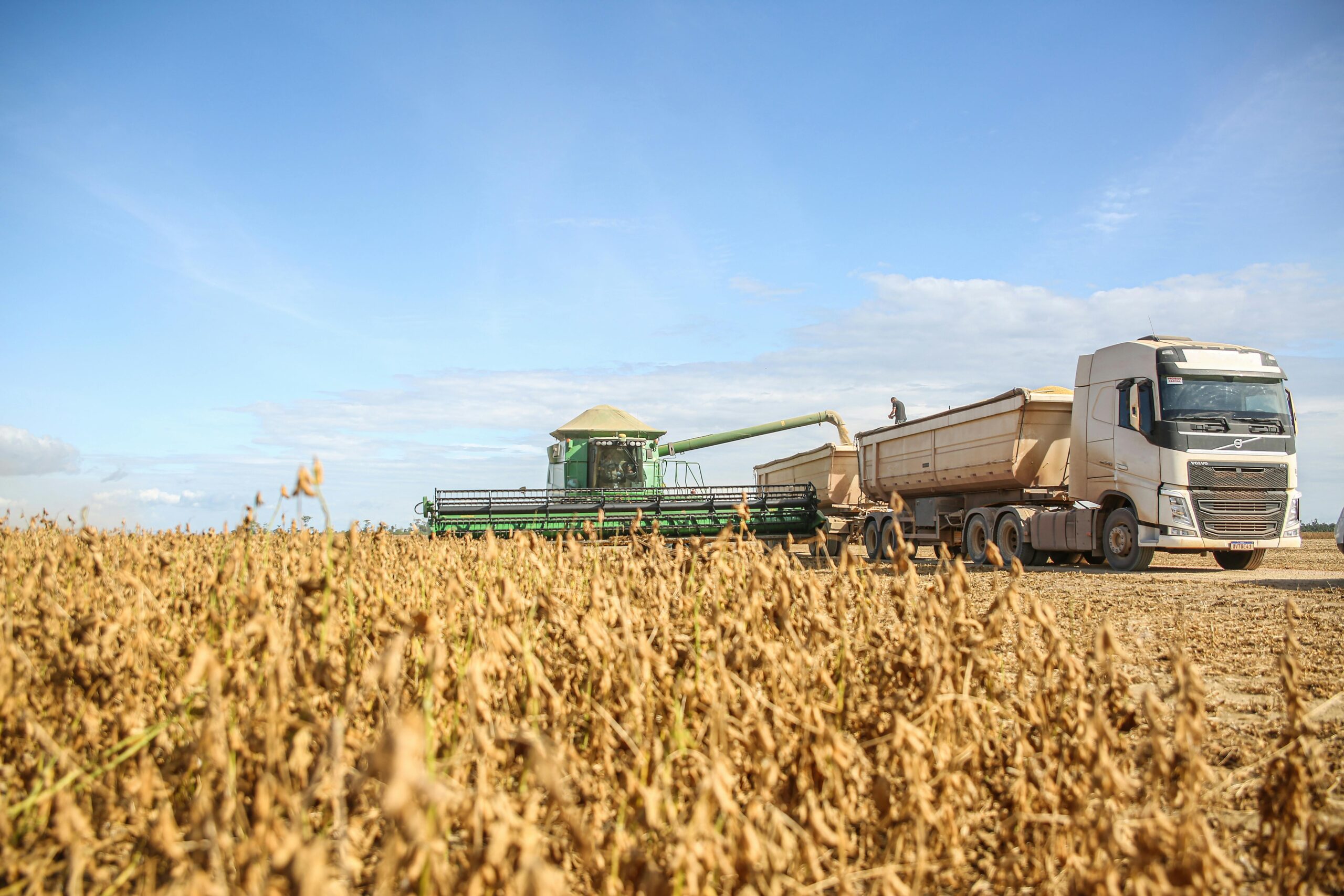 A combine harvester transfers soybeans to a truck during harvest on a sunny day in Paragominas, Brazil.