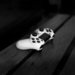 Black and white photo of a gaming controller on a wooden table, perfect for gaming or tech themes.